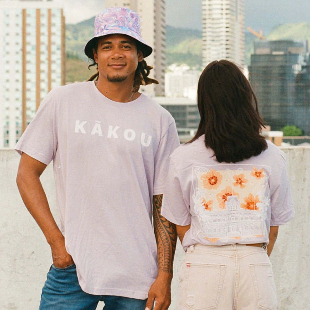 A man and woman wearing floral t-shirts, smiling and standing together outdoors
