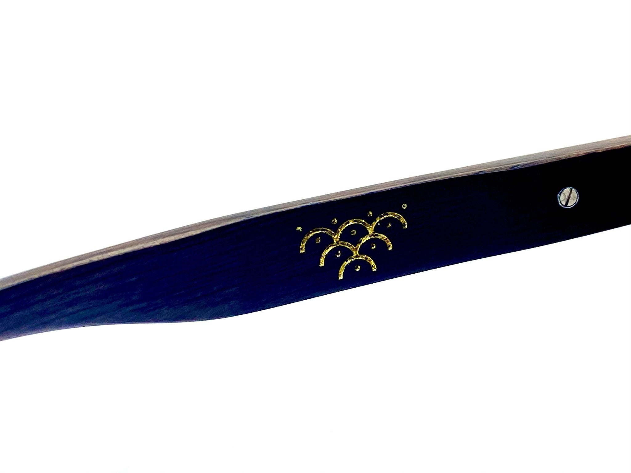 Close-up of Templ sunglasses arm with a gold foil emblem engraved into dark wood, highlighting artisanal craftsmanship and subtle luxury in every detail.