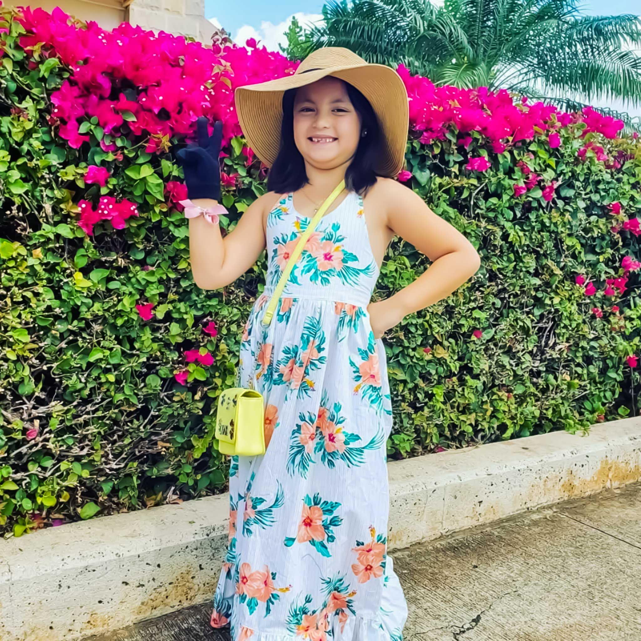 A happy girl wearing the tropical floral dress, styled with a sunhat and playful accessories, radiating sunshine-ready confidence and carefree charm.