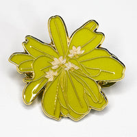 Green flower-shaped pin with gold accents on a white background