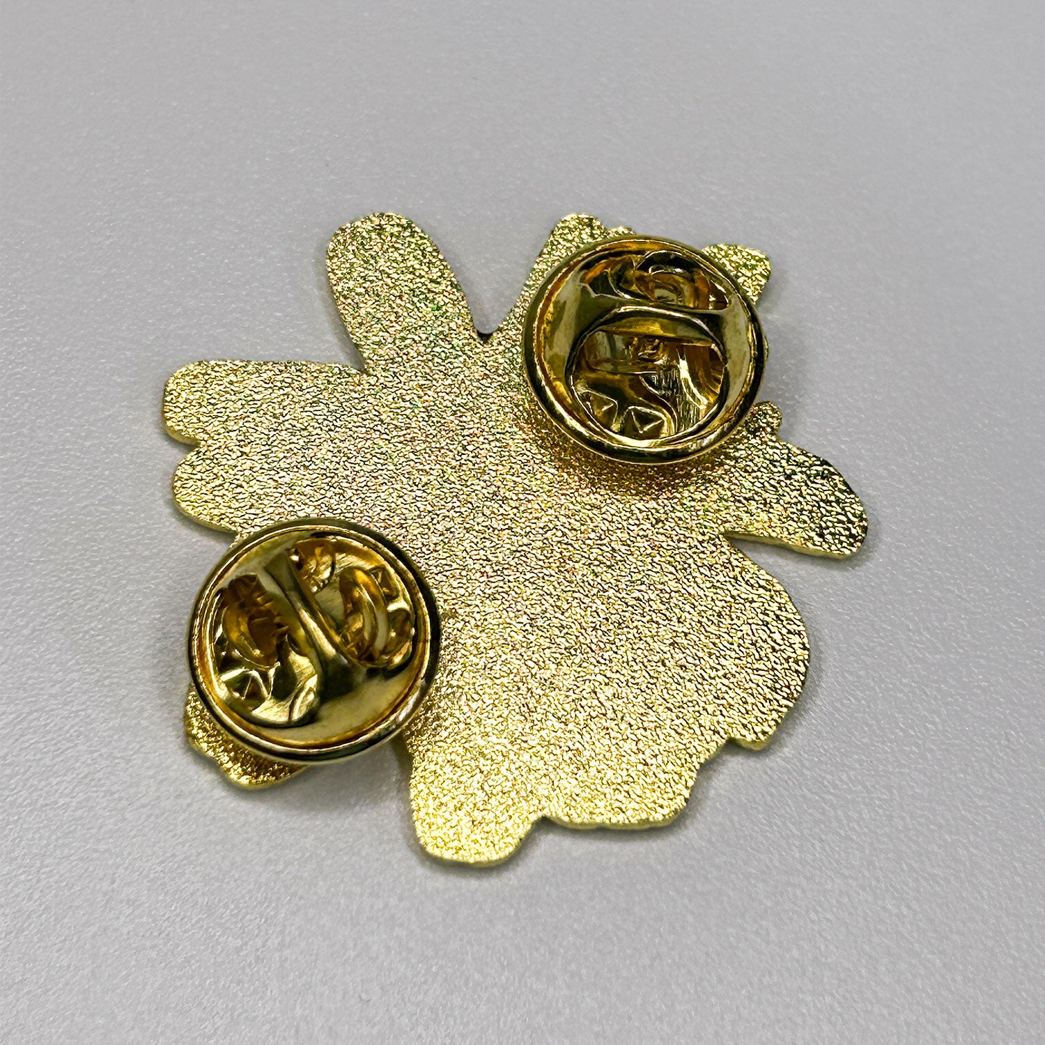 Gold-colored flower-shaped pin on a gray background